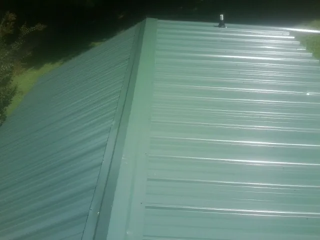 New green metal panels meeting at the ridge of a roof — Flat Roof Repair work by our crew in Hungry Horse