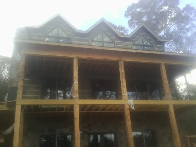 Dormers and porch framing on a large log home under construction — Roof Coating work by our crew in Hungry Horse