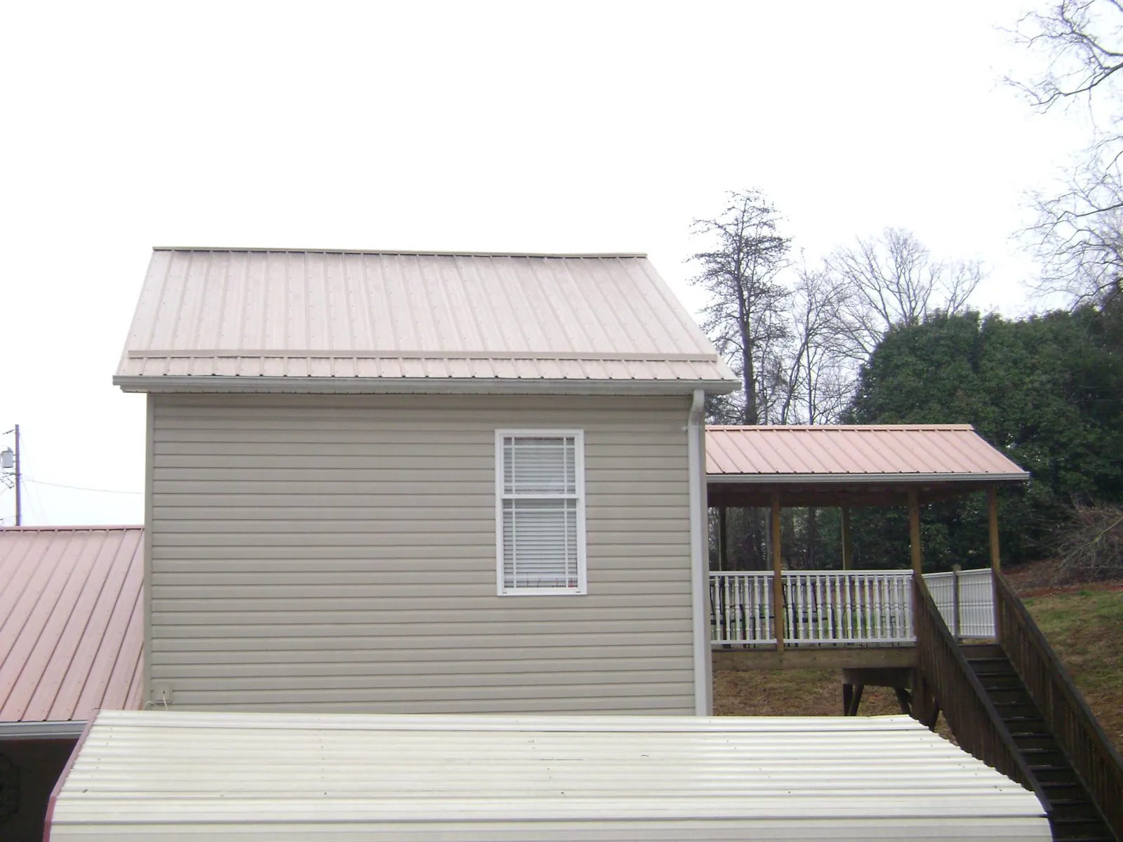 Tan metal roofs on a two story addition and attached porch, from a Roof Replacement job in Hungry Horse