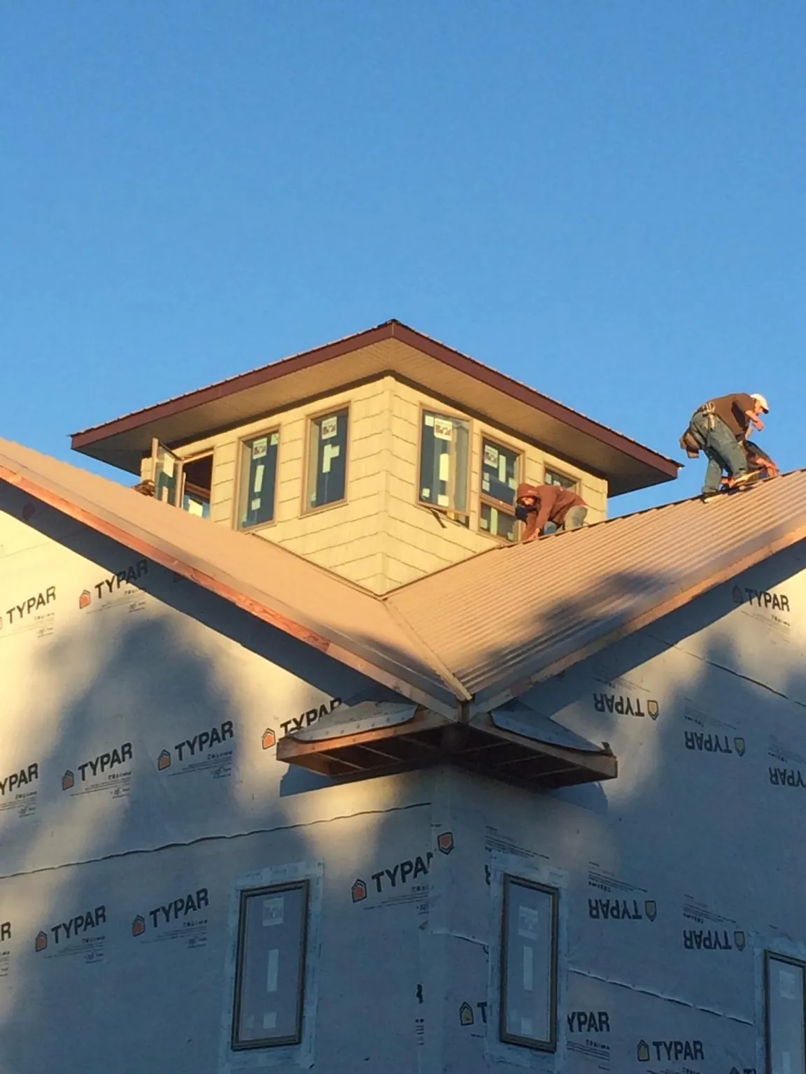Roofers working around a rooftop cupola on a new metal roof at sunset — Roof Waterproofing in Hungry Horse by Roofing Brothers